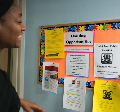 Guest Resources a woman looking at Housing Opportunities bulletin board