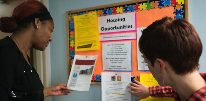 2 women looking at Housing Opportunities bulletin board