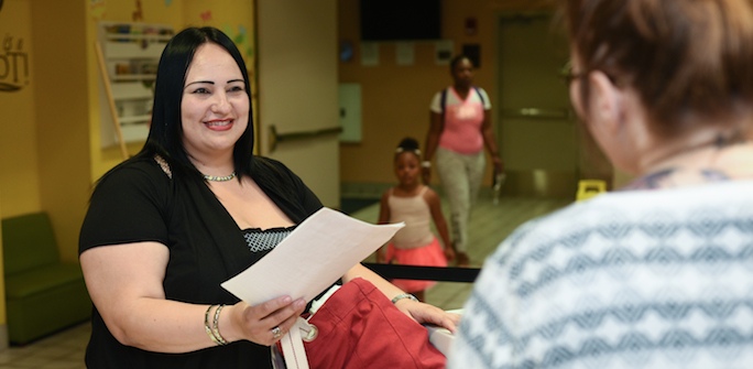 a woman handing paperwork to another