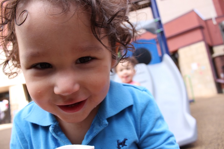 Closeup of boy in front of slide. Girl on slide in background.