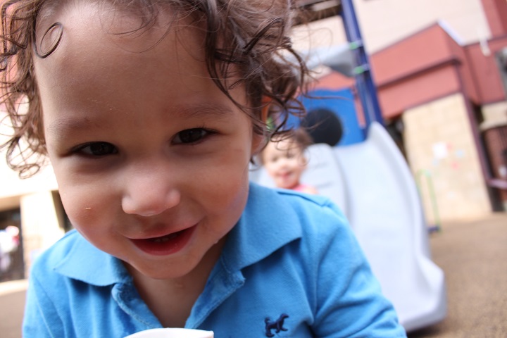 Closeup of boy in front of slide. Girl on slide in background.