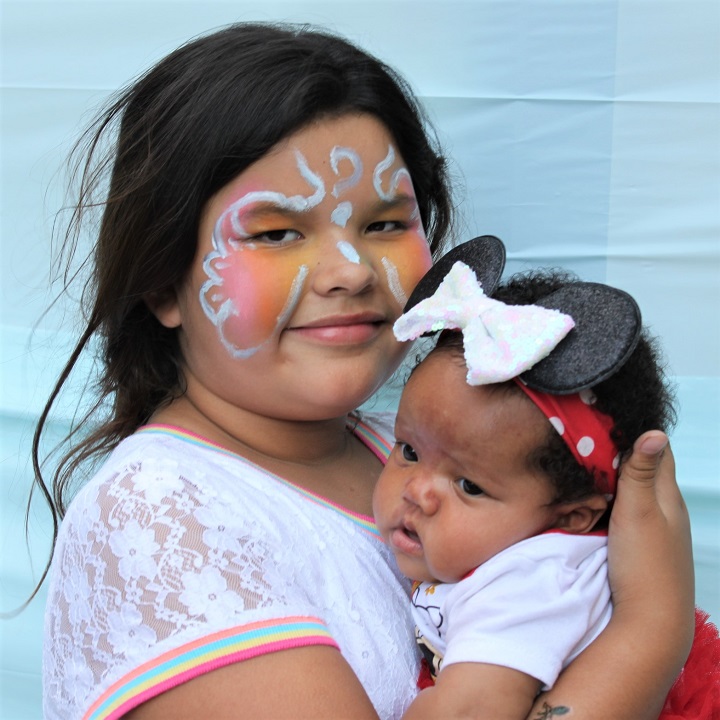 Girl & baby sister posing in photo booth