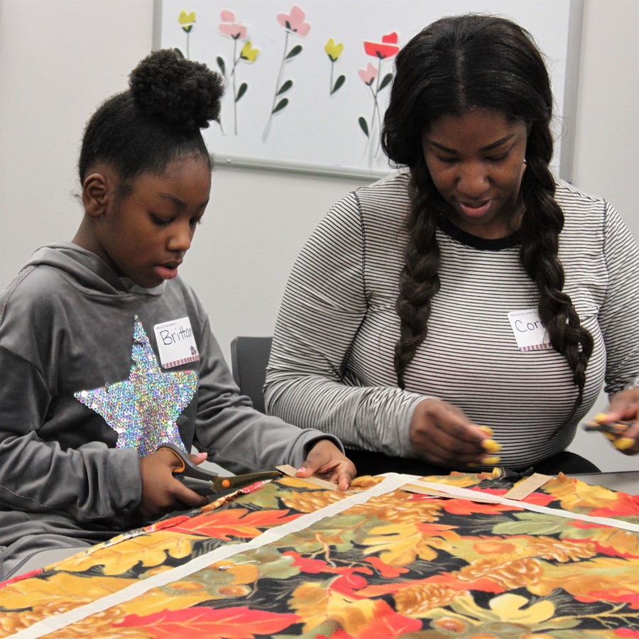 mother & daughter working on a fleece tie-blanket