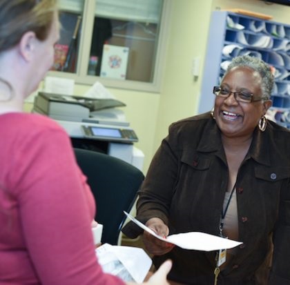 a woman handing paperwork to another