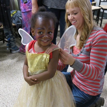 toddler being fitted with angel wings by volunteer