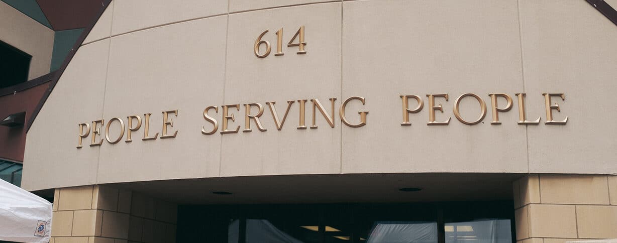 Building entrance with "614 PEOPLE SERVING PEOPLE" in large letters above the doorway.