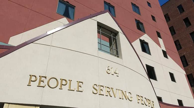 The entrance of a building with "614 PEOPLE SERVING PEOPLE" written in gold letters above the doorway.