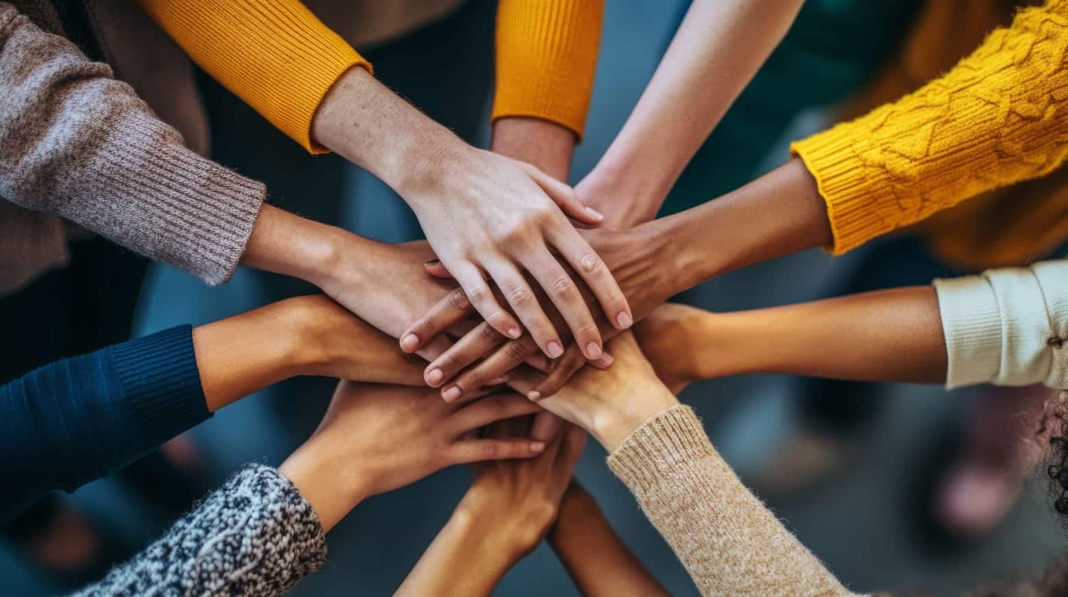 A group of diverse people stacking their hands together in a gesture of unity and teamwork.