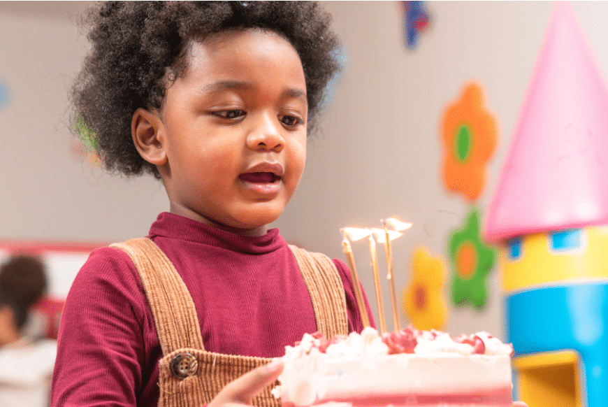 Child holding birthday cake with lit candles