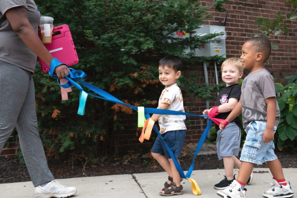 Toddlers walking with preschool teacher